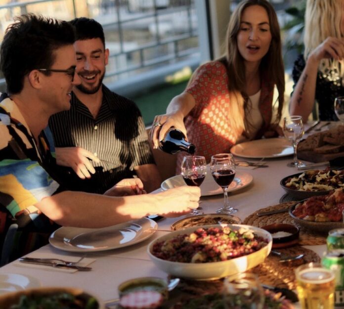 people eating at a table, refilling wine glasses